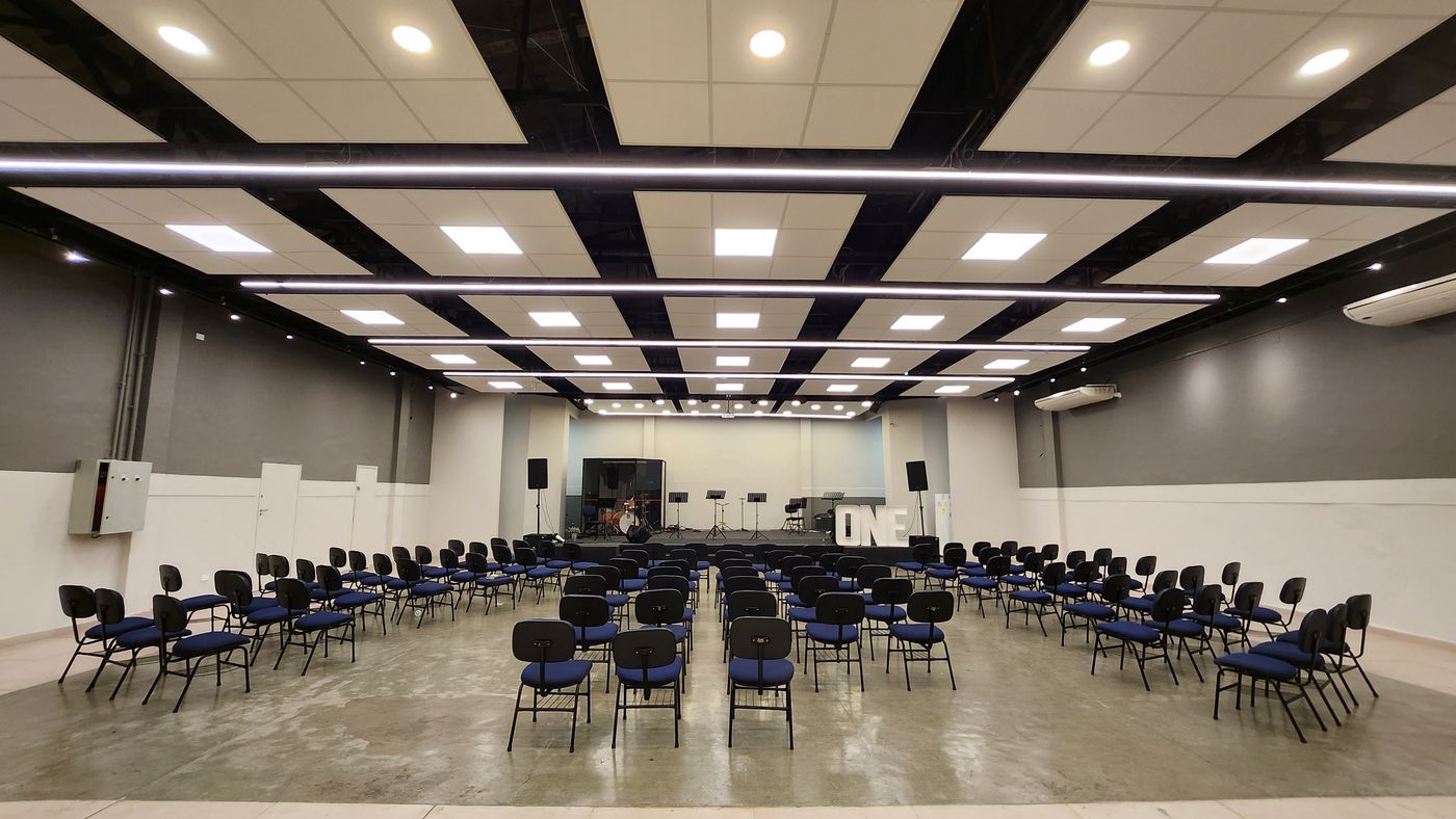 Auditório IMOSP com iluminação Blinkie: perfis lineares pendentes, painéis e spots embutidos no forro